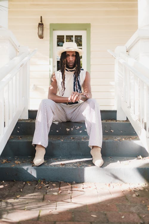 Free Man with Dreadlocks Sitting on Stairs to American Residential House Stock Photo