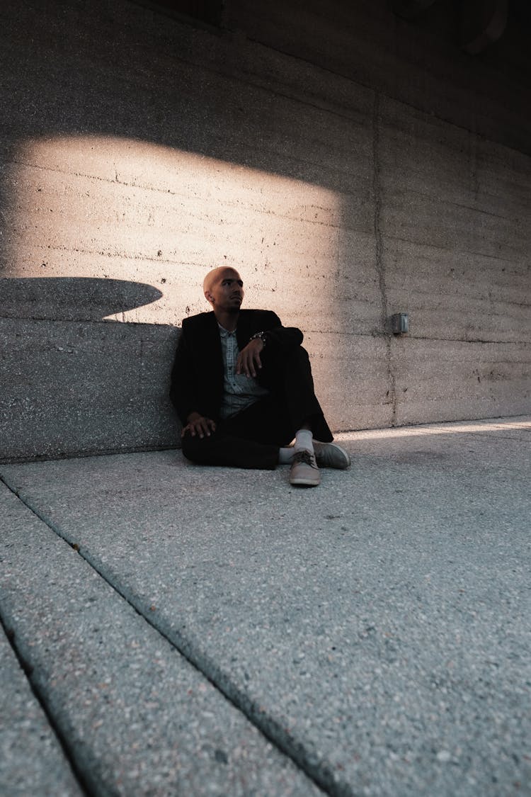 Man Sitting On The Ground And Leaning On The Wall