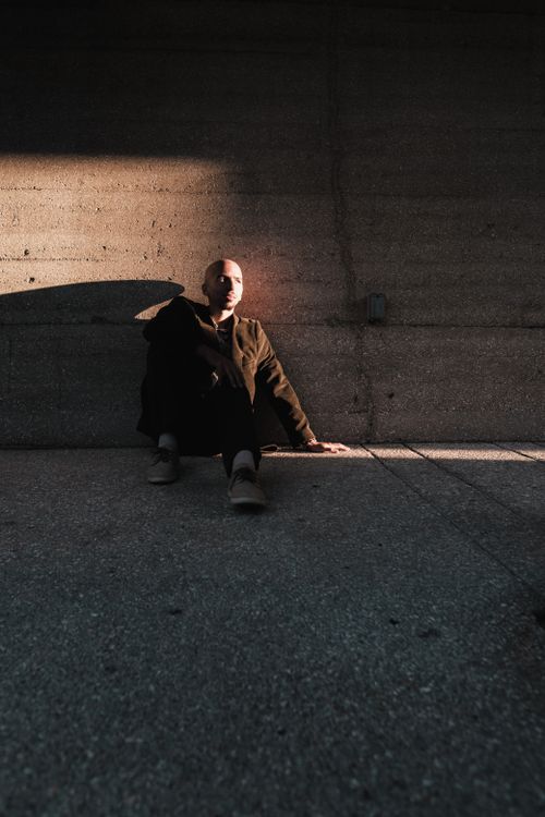 Free Atmospheric portrait of a man sitting against a concrete wall at dusk in St. Augustine, Florida. Stock Photo