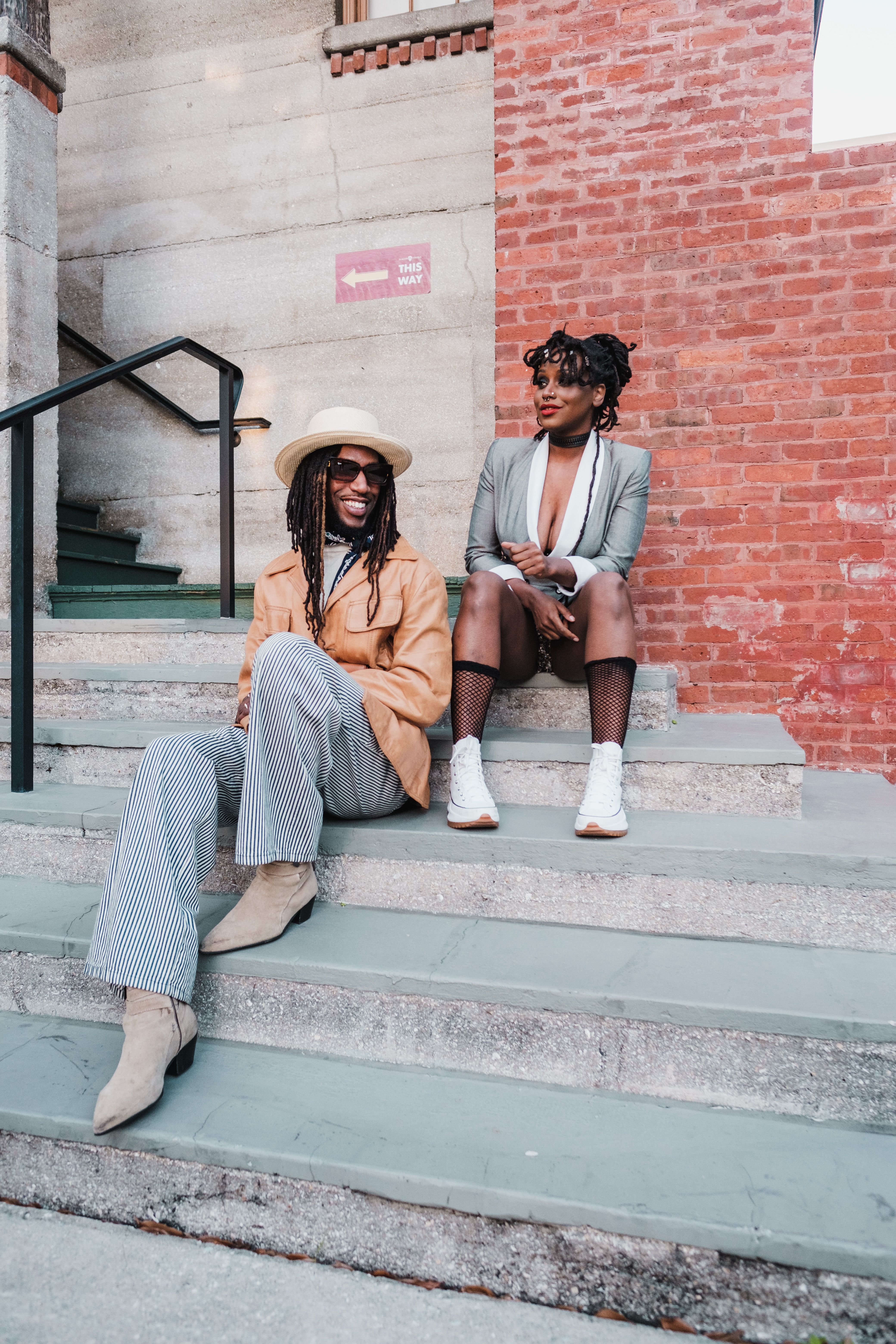 stylish man and woman sitting on stairs