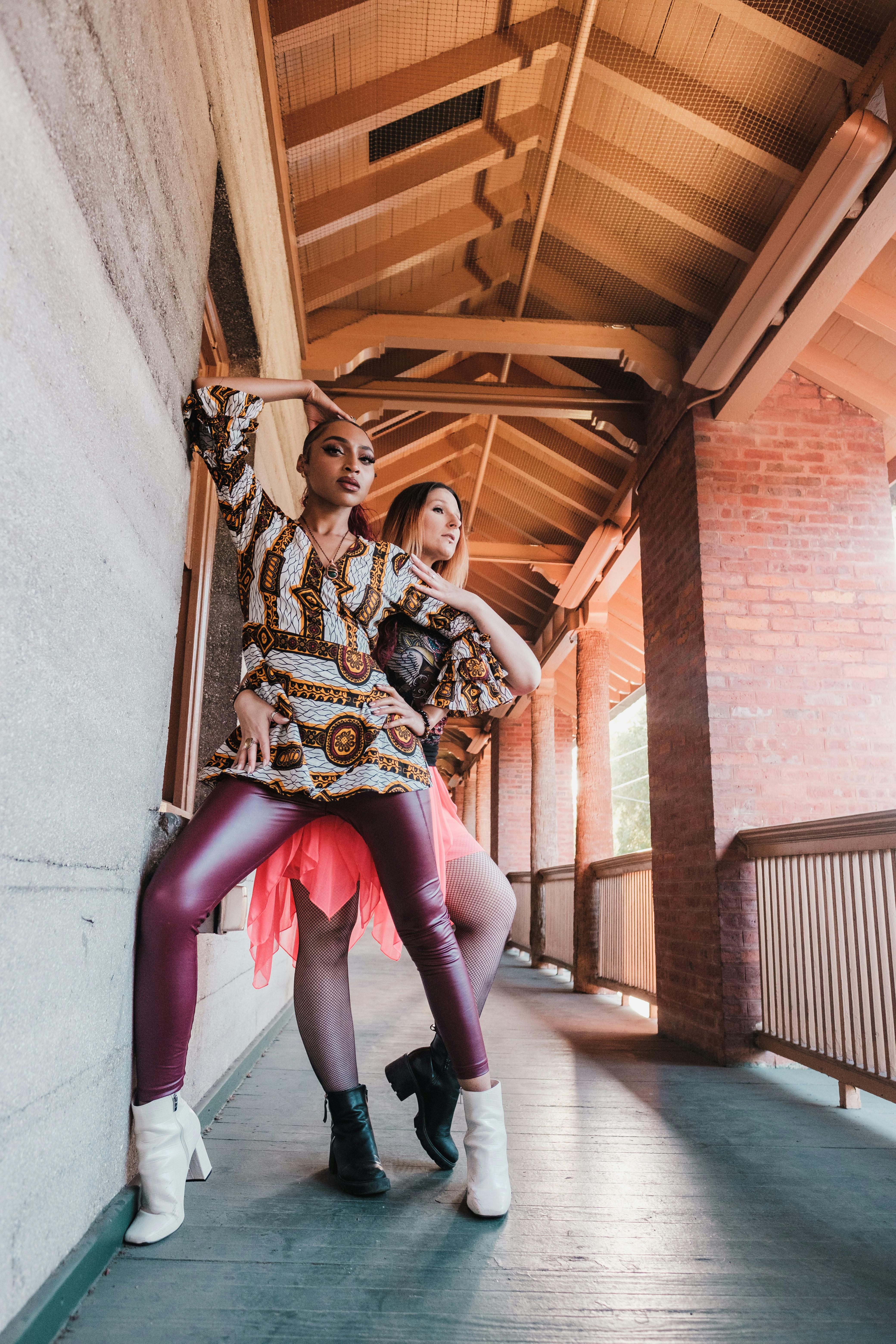 two women posing with gestures for fashion photo on balcony