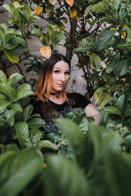 Woman with Surprised Face Hiding in Green Shrub