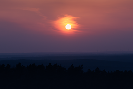 A breathtaking sunset view over a forest with vivid colors and dramatic sky.