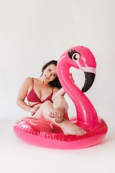 A woman in swimwear enjoying a relaxing moment on a pink flamingo pool float indoors.