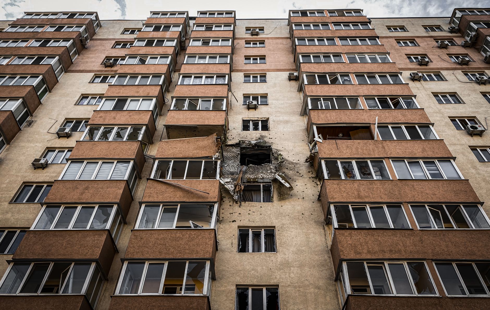 Low-angle view of a damaged apartment building in Kyiv, Ukraine with visible destruction.