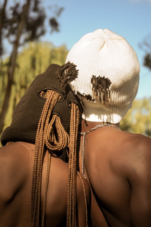 A Back View of Two Shirtless Persons in Balaclava and White Knitted Cap
