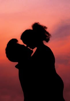 Silhouette of a couple kissing against a vibrant sunset sky in Kolkata.