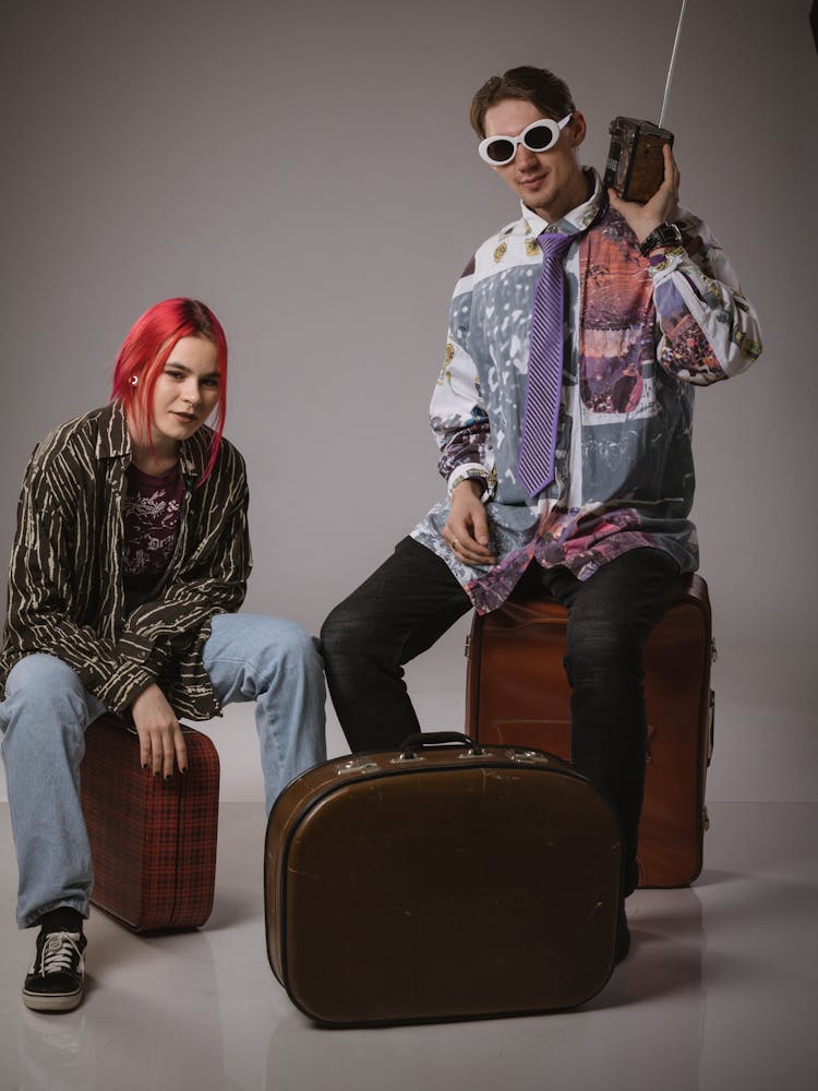 Man And Woman Sitting On Suitcases 