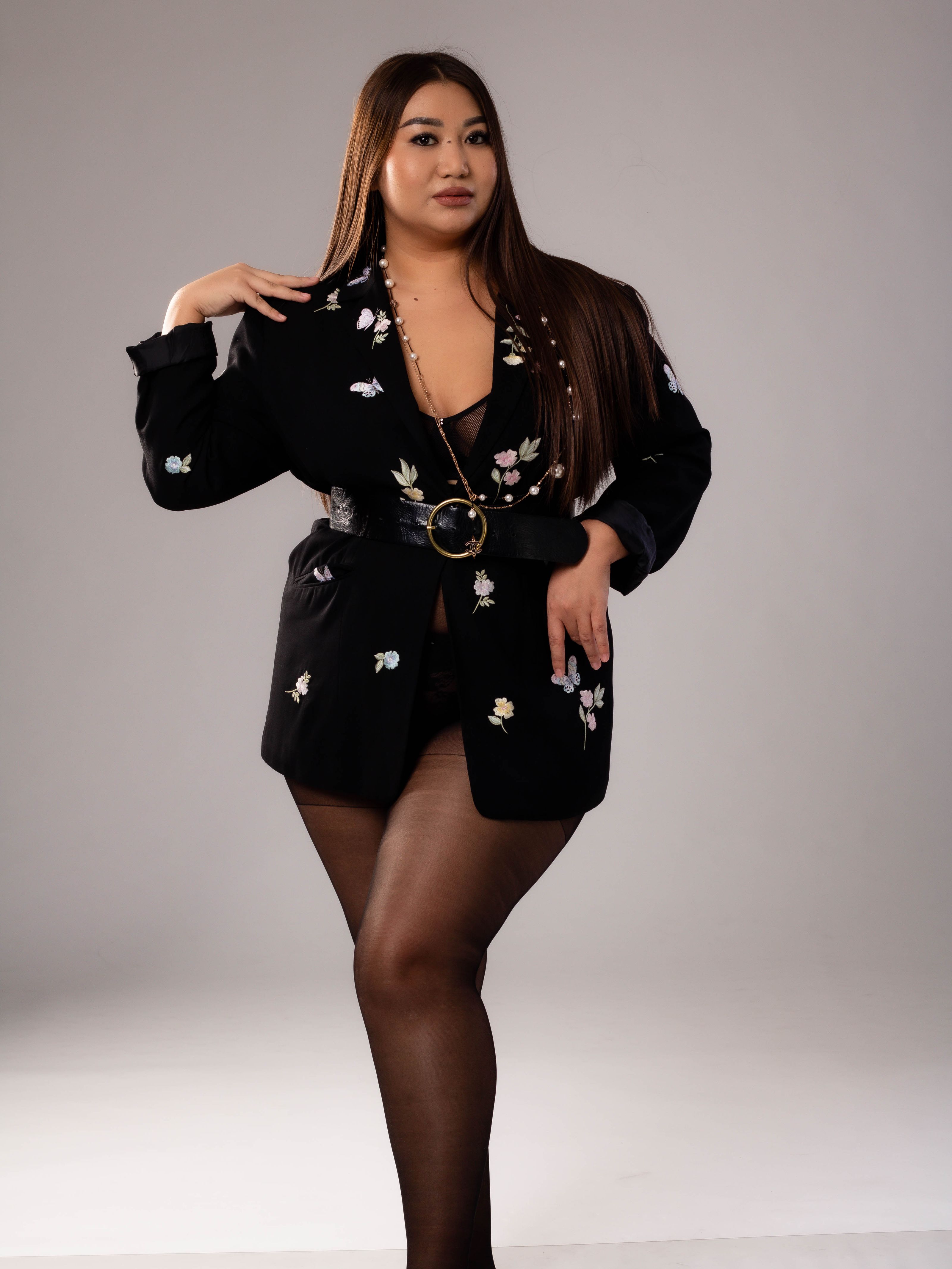Modelo plus size estilosa em jaqueta floral e meias posando em um estúdio.