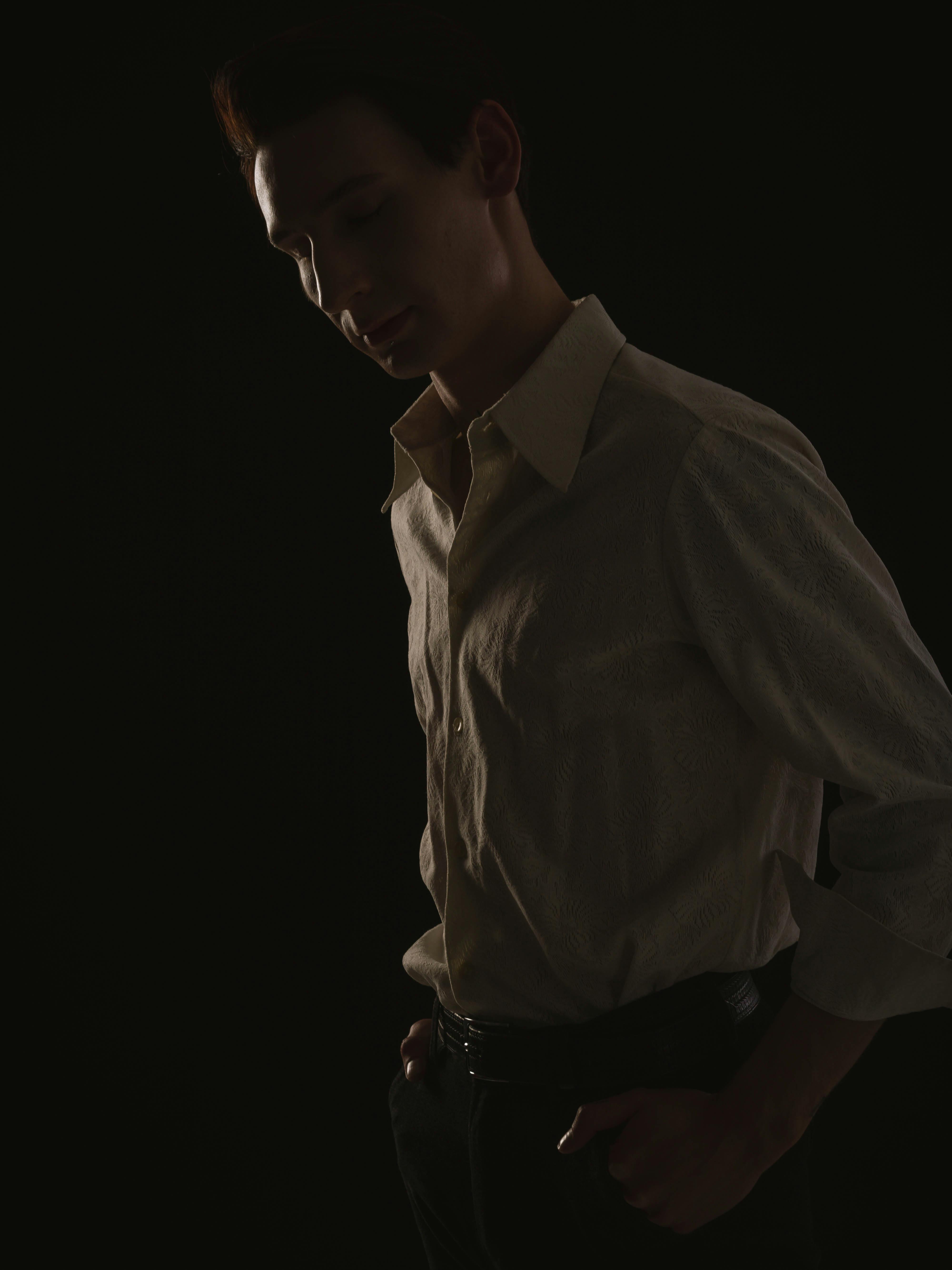 Sophisticated studio portrait of a young man in a stylish shirt under dramatic lighting.