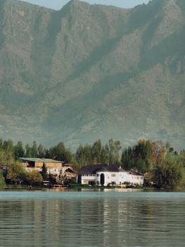 Elegant mansion by a serene lake with majestic mountains in the background.