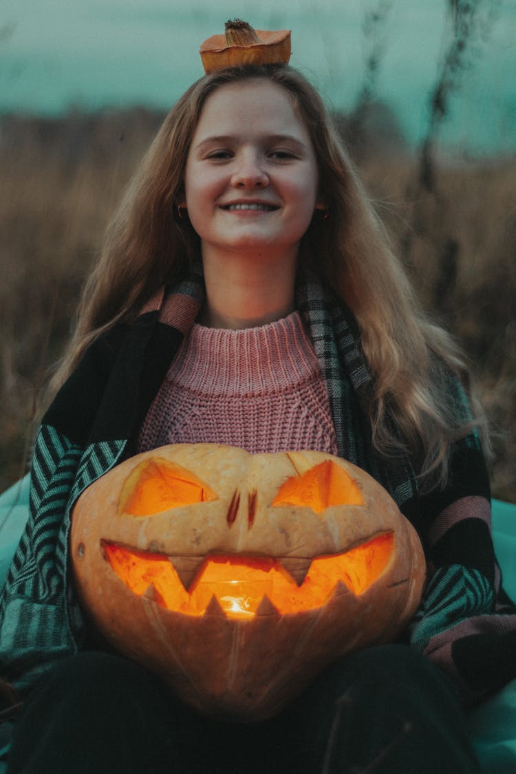 Girl Holding Carved Pumpkin For Halloween