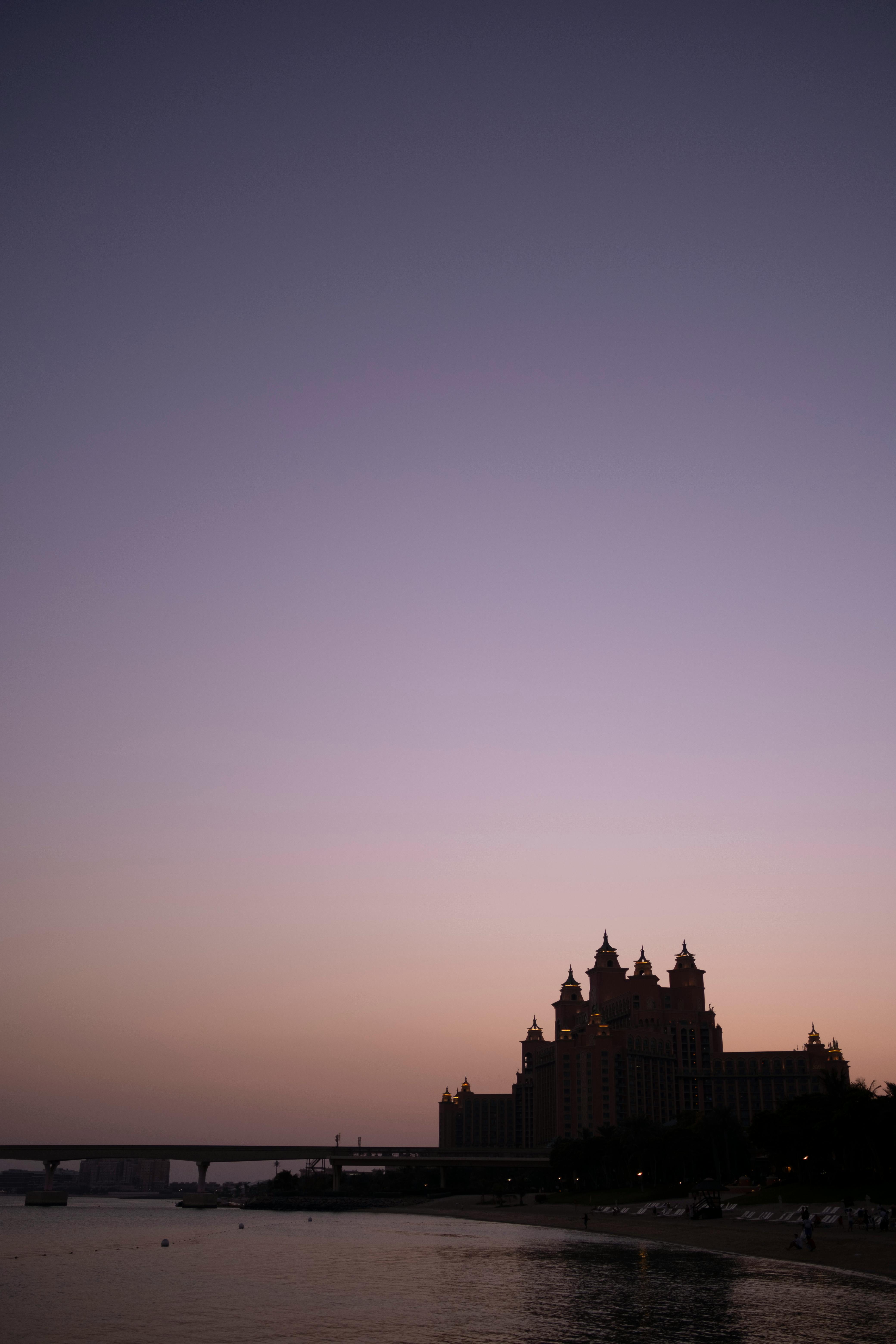 Dramatic sunset view of the iconic Atlantis Hotel silhouetted against a pastel sky in Dubai.