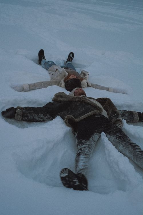 Free Two adults make snow angels in the Russian winter, enjoying playful moments outdoors. Stock Photo