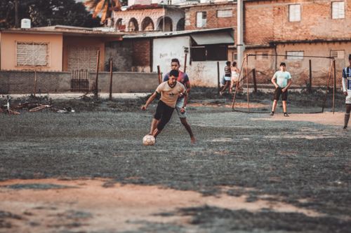 Free A group of men playing soccer on a makeshift field in an urban neighborhood. Stock Photo