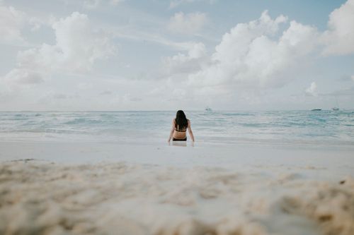 Free A woman enjoys a peaceful moment by the ocean on a sandy beach in Cancún, Mexico. Stock Photo