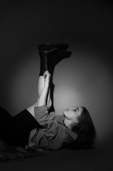 Monochrome portrait of a woman with legs up, wearing boots.