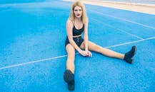 一位金发女子放松地坐在户外充满活力的蓝色网球场上