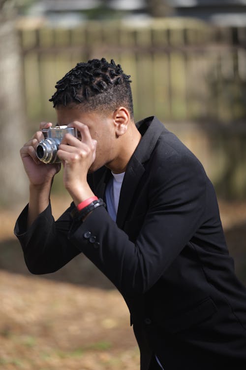 Man in a Black Coat Taking Pictures with a Vintage Camera