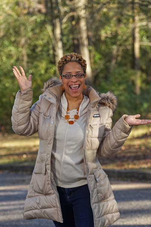 A Woman in Puffer Jacket Smiling while Wearing Eyeglasses
