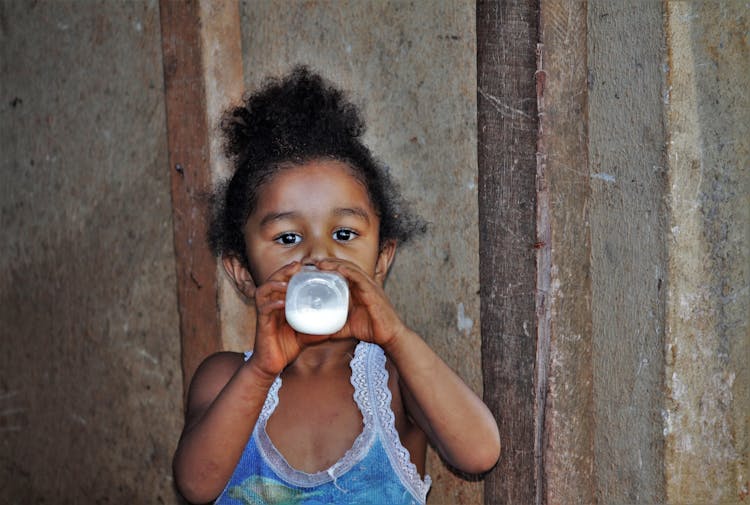 Girl In Blue Tank Top Drinking Milk From A Bottle