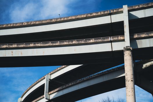 Low angle shot of intersecting highway bridges against a clear blue sky.
