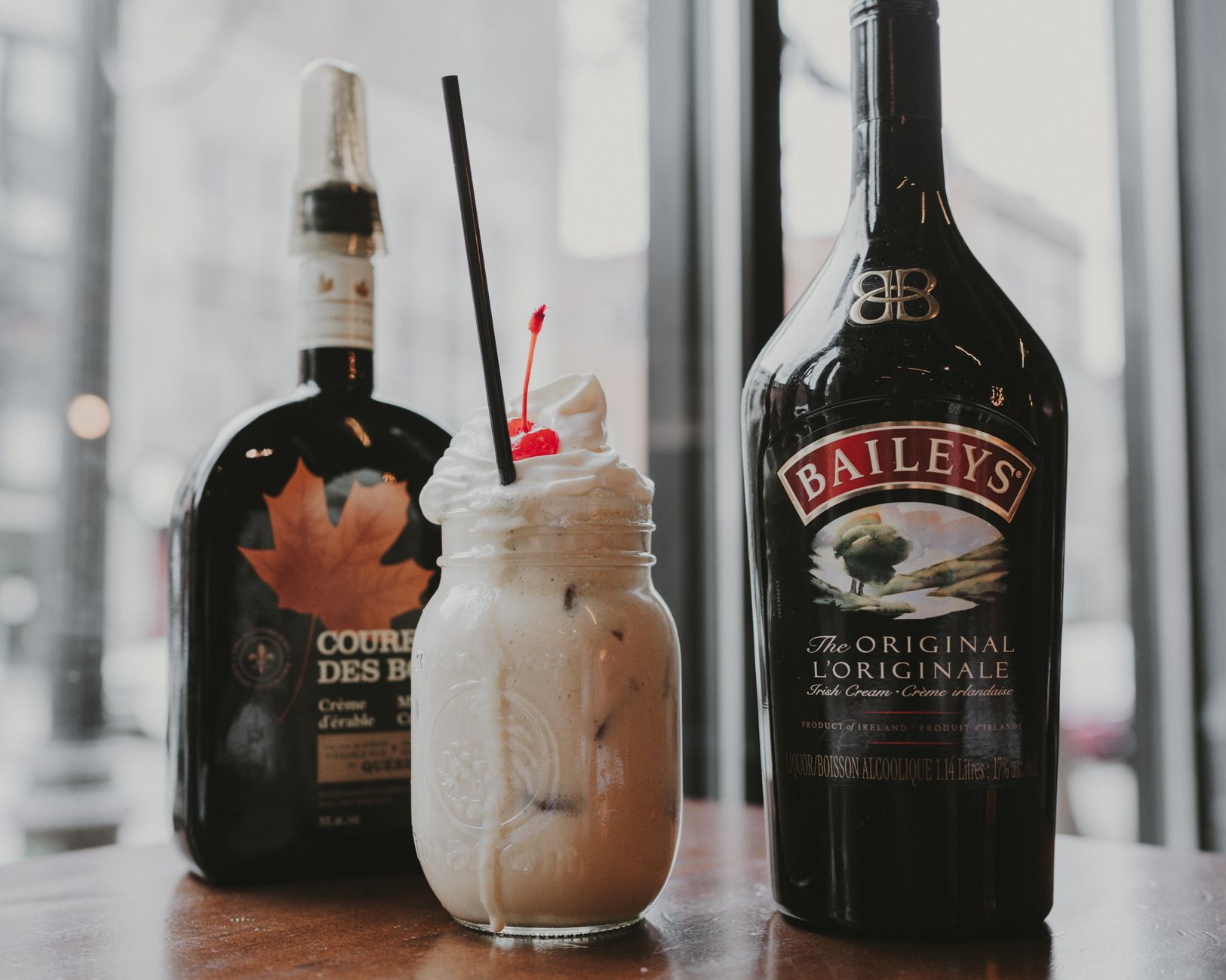 Creamy Baileys cocktail with cherry garnish, captured in a cozy indoor setting. Perfect for dessert drinks.