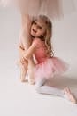 Little Girl in Ballerina Costume Hugging Her Mothers Legs