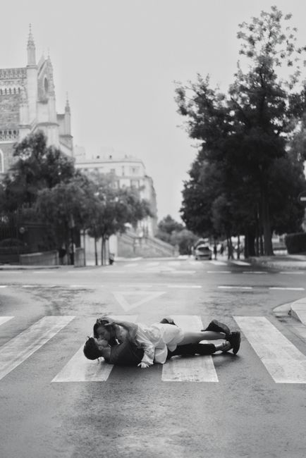 Black and white photo of a couple kissing on an empty city street.
