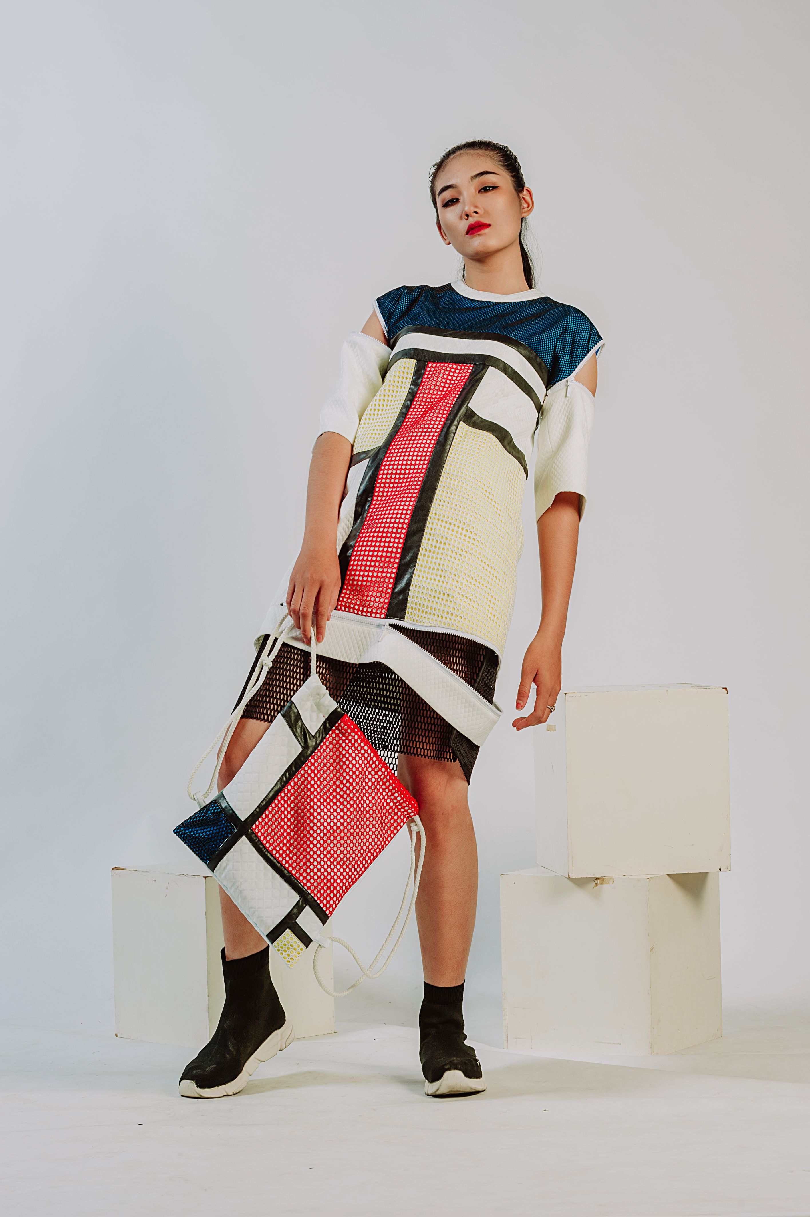 Mulher fashion em um traje moderno posando em um estúdio minimalista.