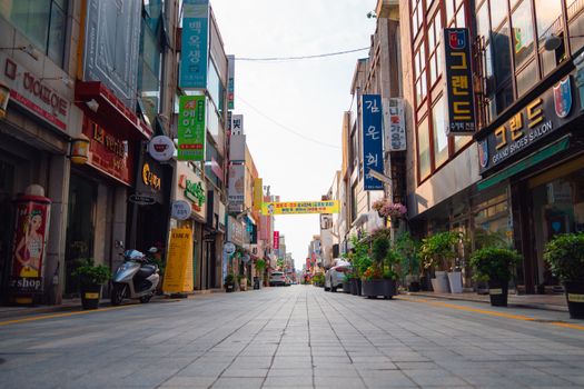 Low-angle view of a lively street with shops and signs in Gwangju, South Korea.