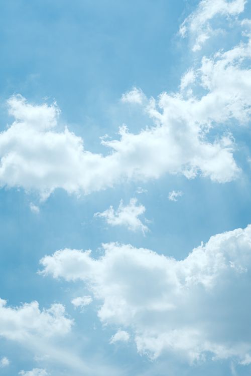 Free Serene blue sky with fluffy white clouds on a sunny day, perfect for relaxation themes. Stock Photo