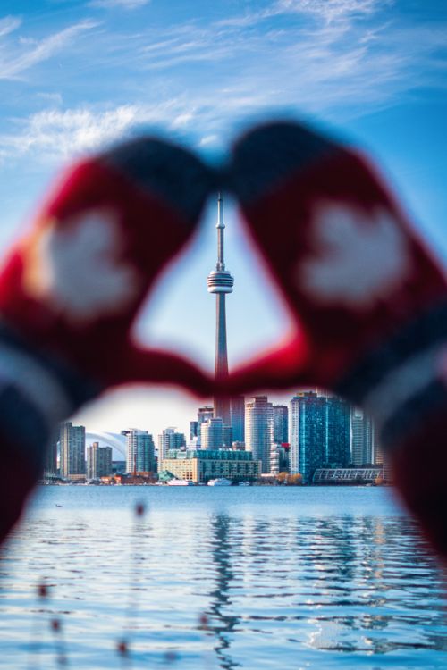 Free Creative view of Toronto skyline with CN Tower framed by hands in mittens forming a heart. Stock Photo