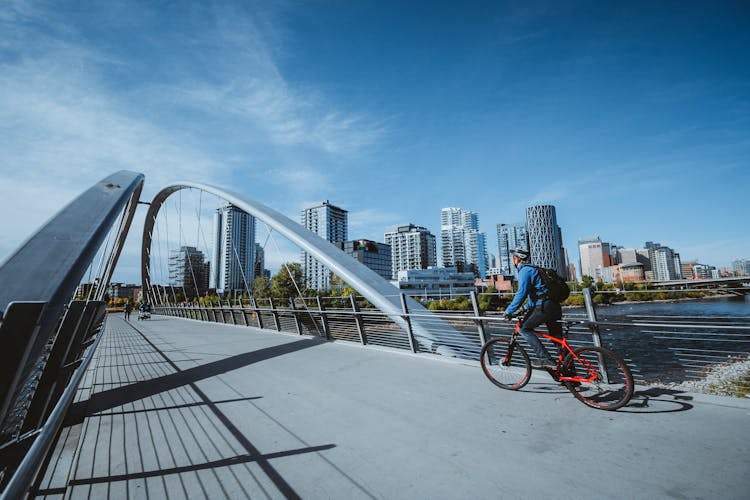 Man Riding Bike Across Modern Bridge