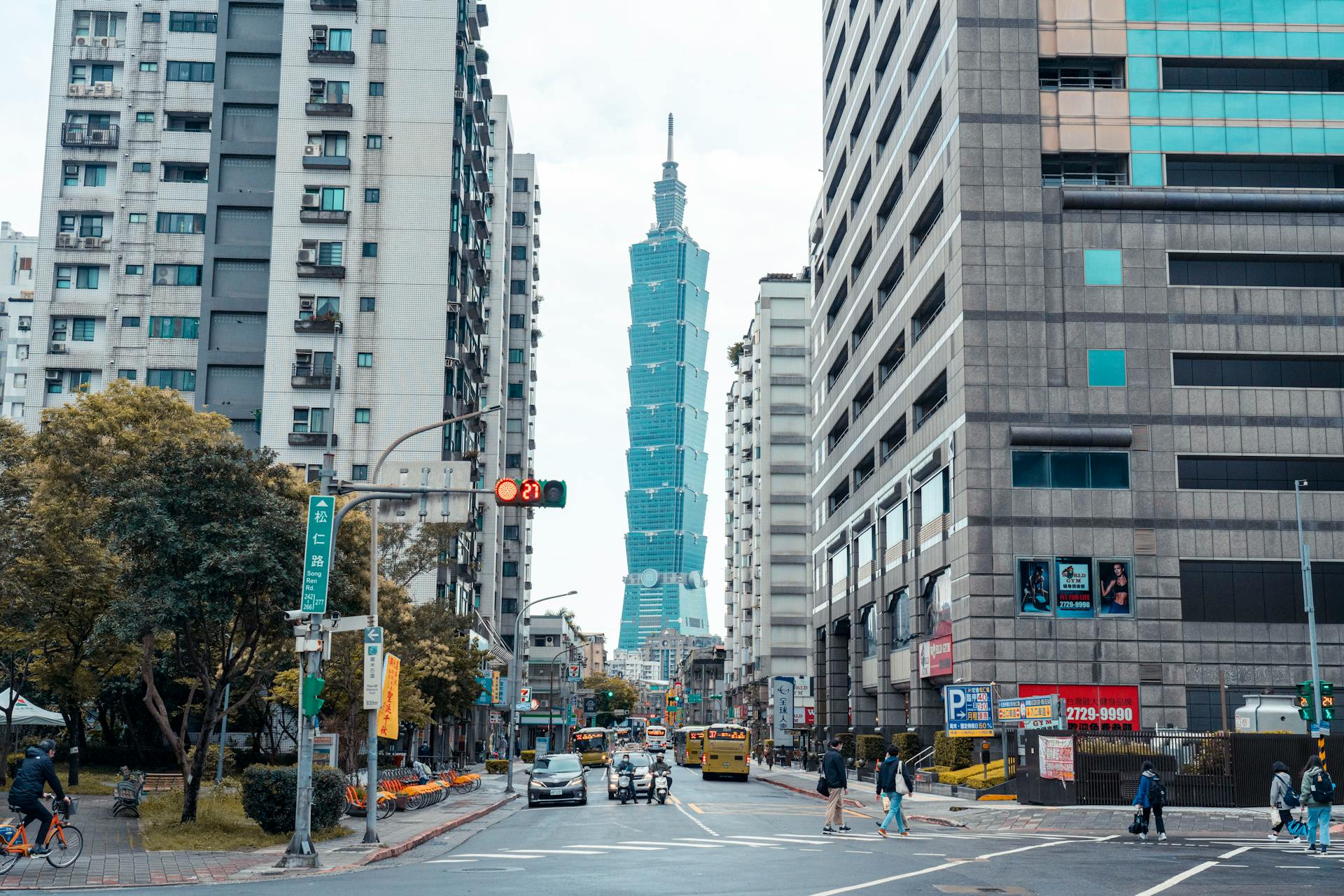 A busy urban street scene in Taipei featuring the iconic Taipei 101 building in the background.