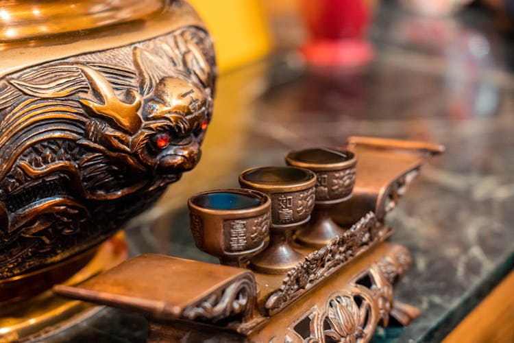 Close Up Of Bronze Chalices And Carving