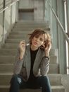 A Woman in Plaid Blazer Sitting on the Stairs