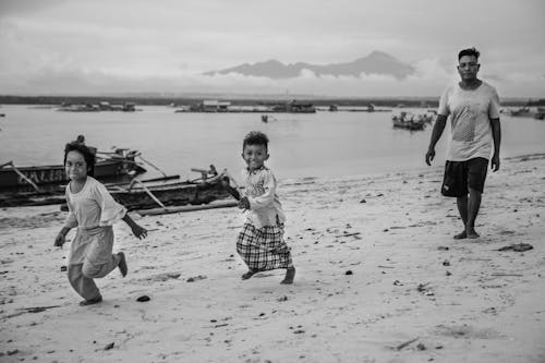 Free Children running on Shore with their Father behind them  Stock Photo