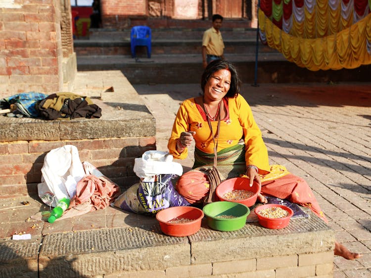 Smiling Woman Sitting On The Street Selling Food 