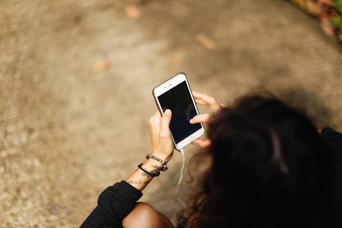 Akıllı telefon tutan bir oyuncunun elleri, açık hava ortamında
