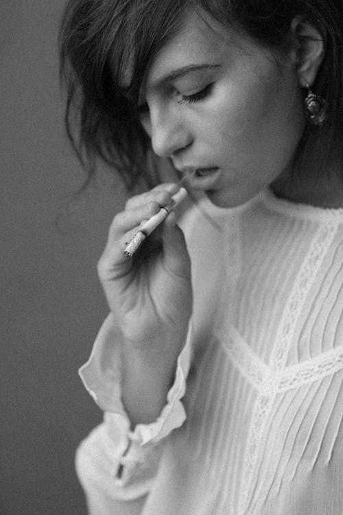A Woman in White Long Sleeves Smoking Cigarette