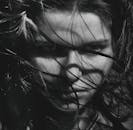 这幅迷人的灰色肖像描绘了一位吹着头发的女人，流露出神秘而强烈的气息