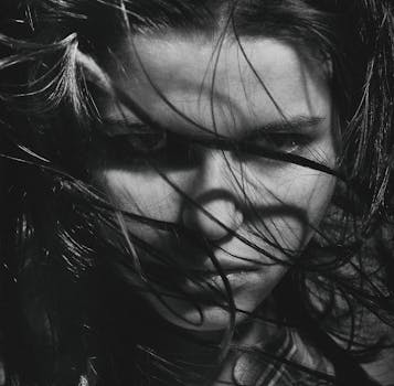 这幅迷人的灰色肖像描绘了一位吹着头发的女人，流露出神秘而强烈的气息