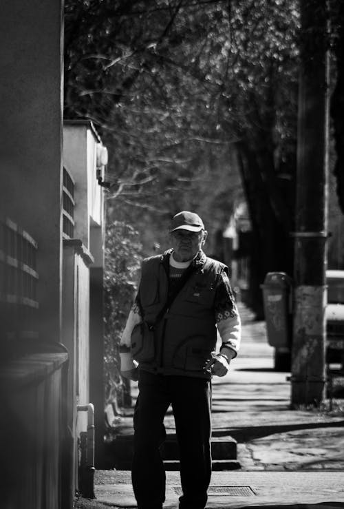 Free Grayscale Photo of an Elderly Man Walking on Sidewalk Stock Photo