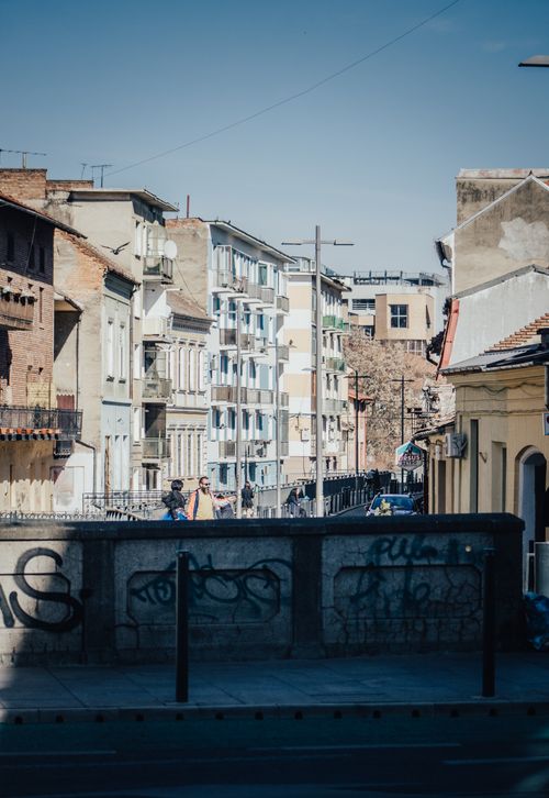 Free A vibrant urban street scene featuring residential buildings, clear blue sky, and street graffiti. Stock Photo
