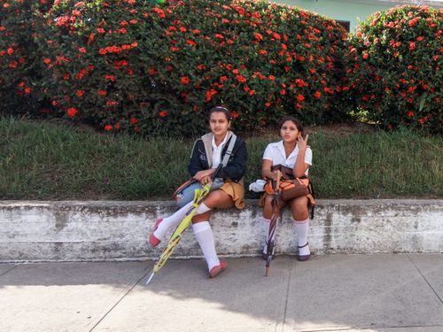 Free Two young female students sitting on a ledge with colorful umbrellas in a garden area. Stock Photo