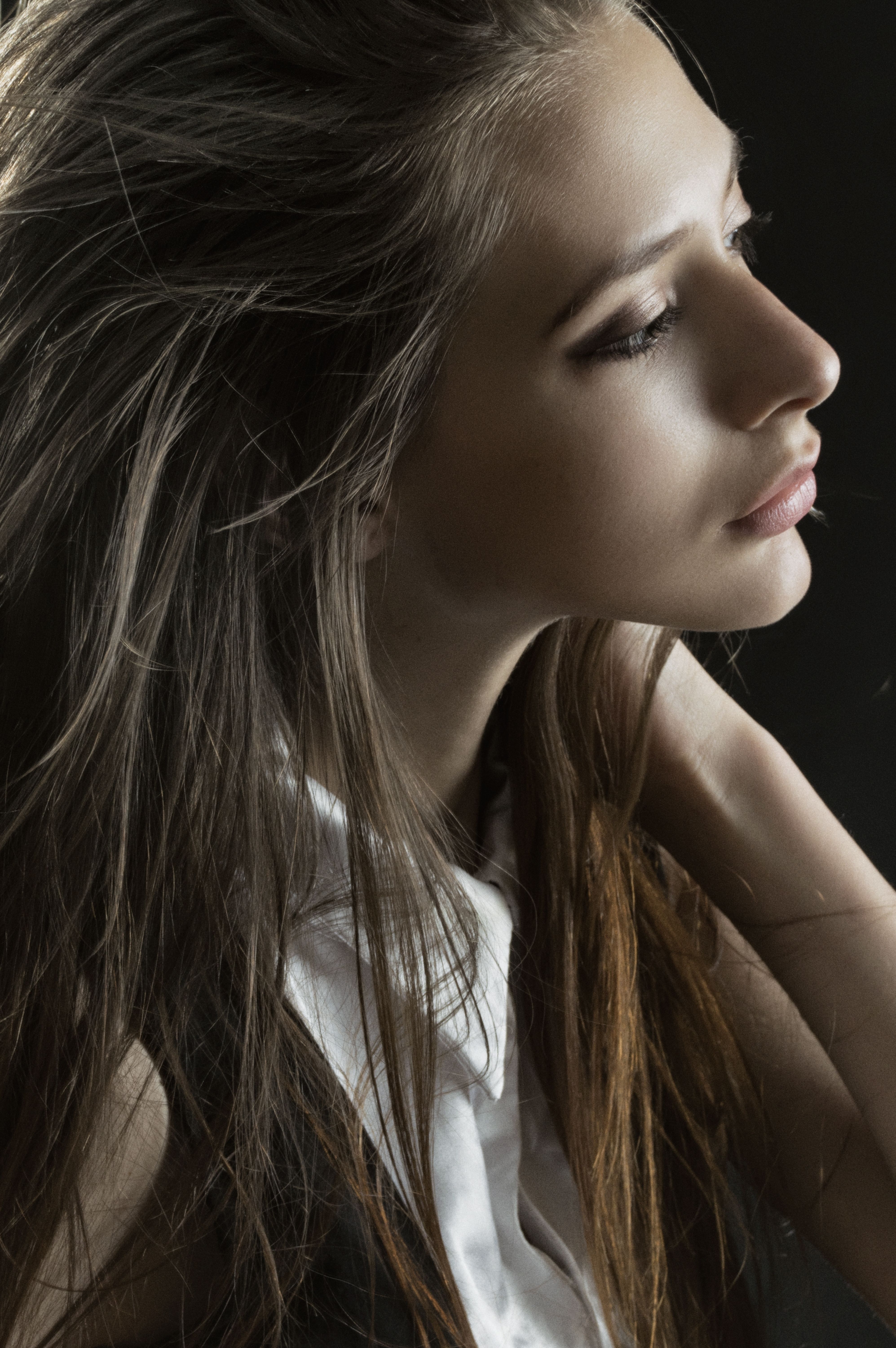 Side profile portrait of a young woman with long hair, offering a serene and graceful look.
