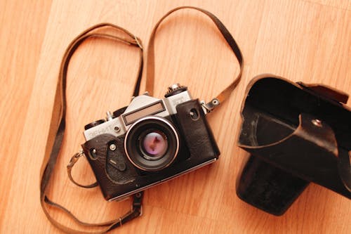 Black and Silver Dslr Camera on Brown Wooden Surface 