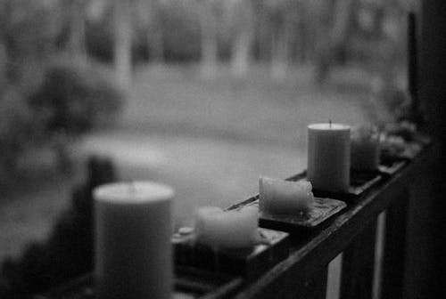 
A Grayscale of Candles on a Railing