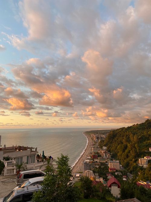Free Beautiful sunset over coastal town with orange clouds reflecting on the sea. Serene and picturesque. Stock Photo